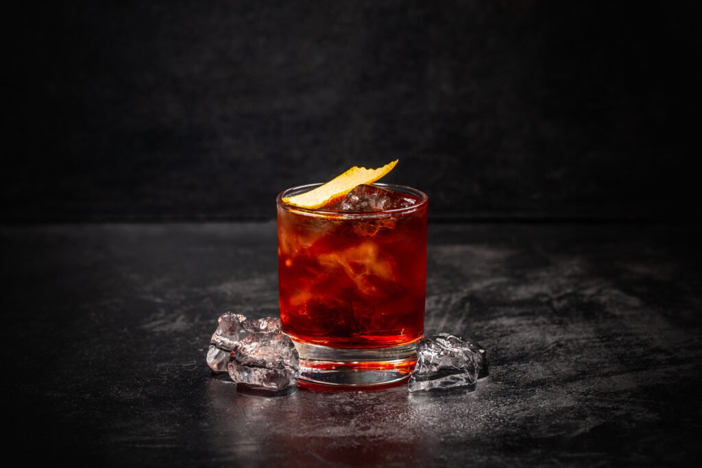 Negroni with orange peel at a dark cocktail bar.